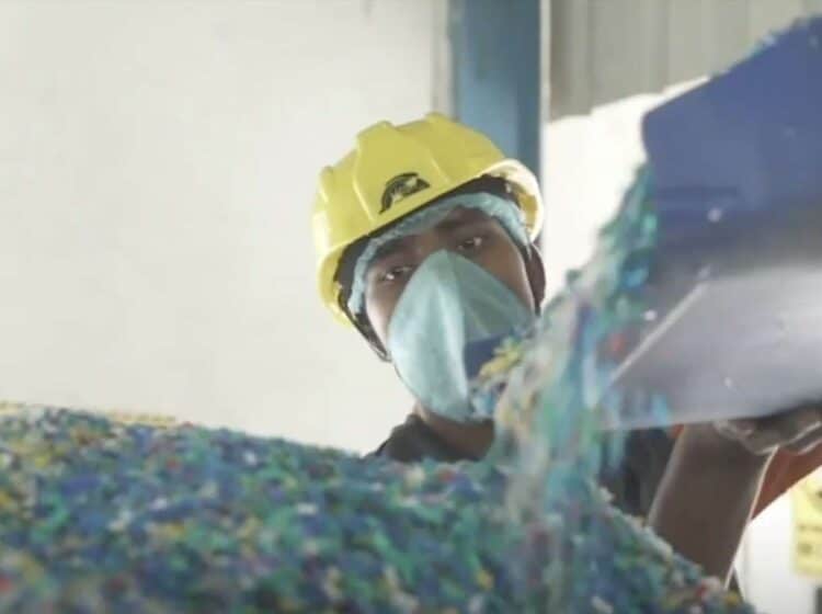 Photograph of worker in facility working with plastic flakes