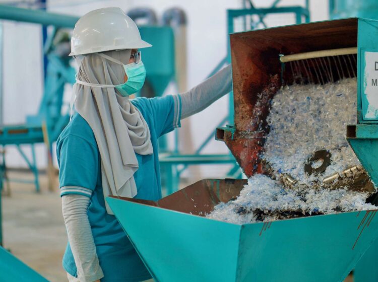 Photograph of woman with mask running plastic sorting machine