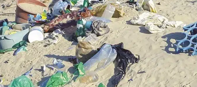 Photograph of plastic and other waste in the sand of a beach
